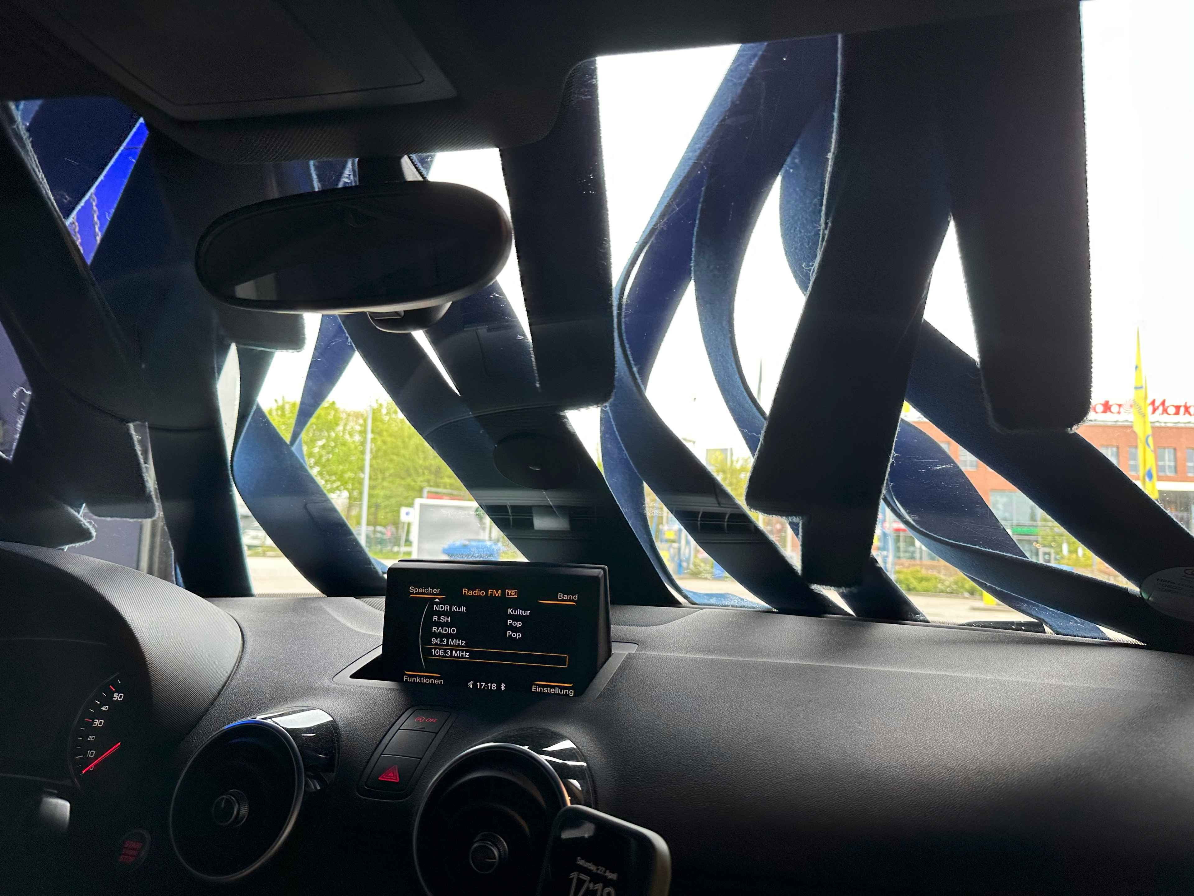Sicht aus dem Inneren eines Autos in einer Autowaschanlage mit blauen Stoffstreifen, die die Windschutzscheibe abtrocknen.