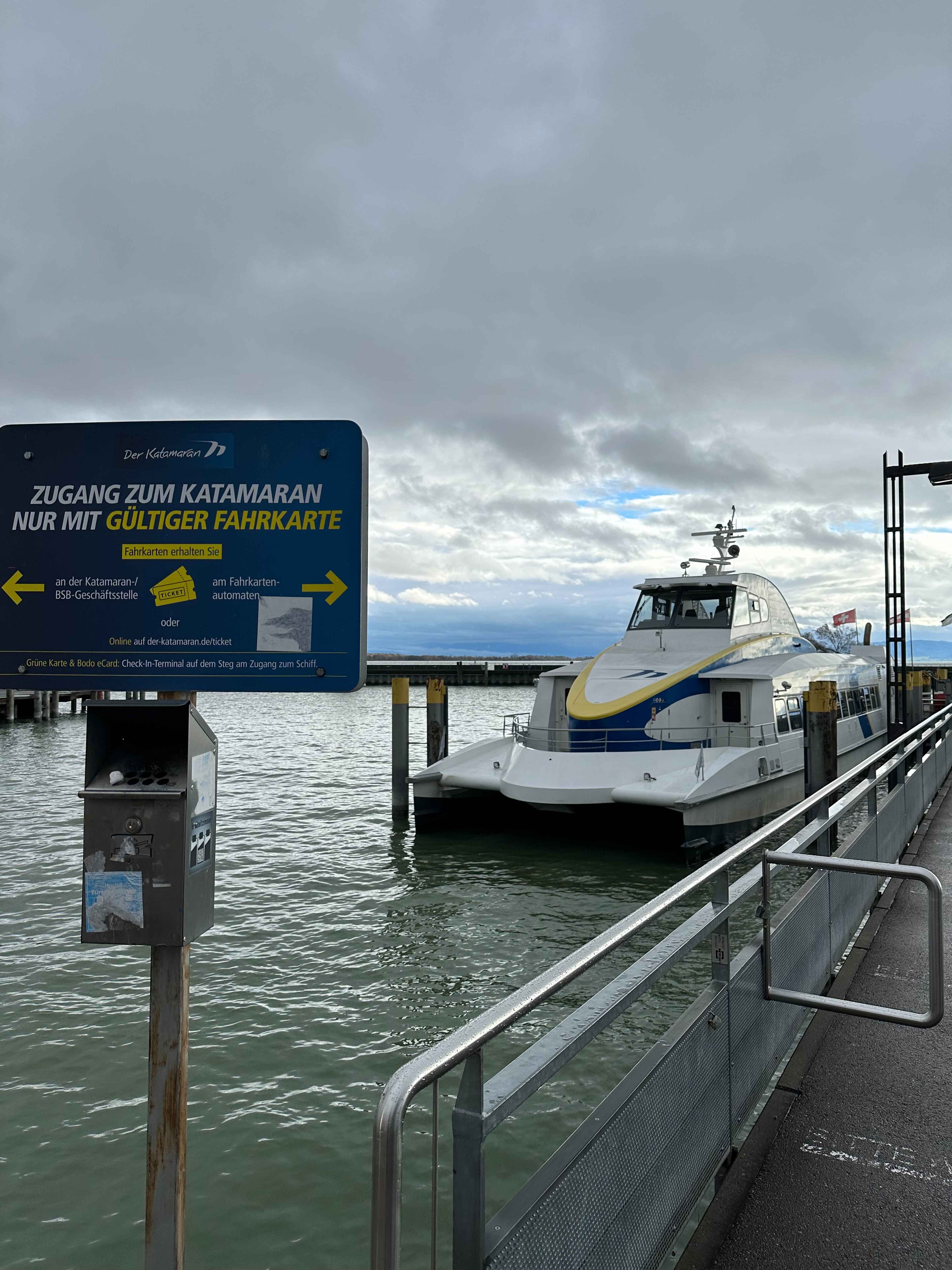 Ein Katamaran liegt an einem Steg vor einem Schild mit der Aufschrift "Zugang zum Katamaran nur mit gültiger Fahrkarte".