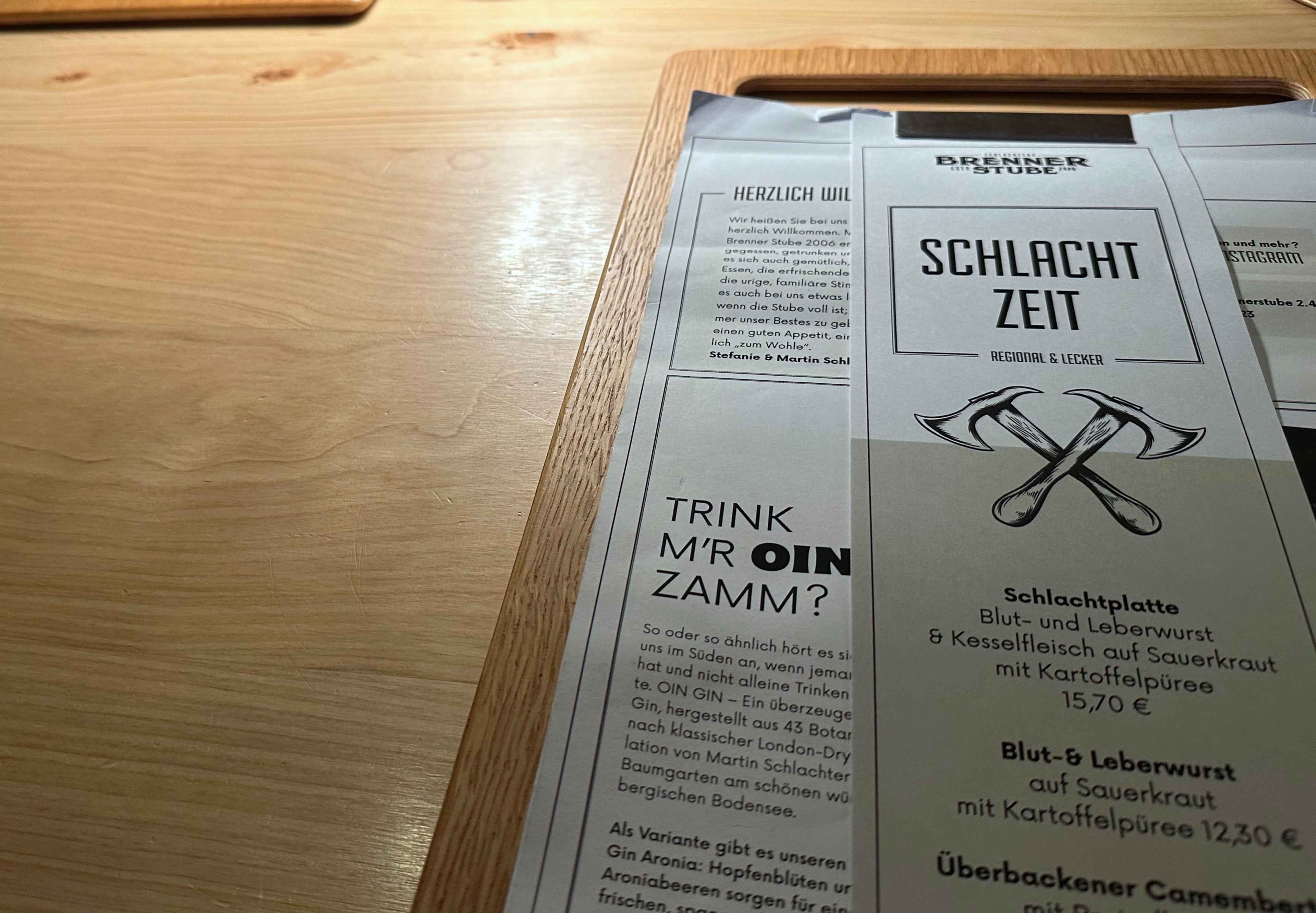 Eine Speisekarte mit der Überschrift "Schlachtzeit" und gekreuzten Hacken, darunter traditionelle Gerichte mit Preisen.
