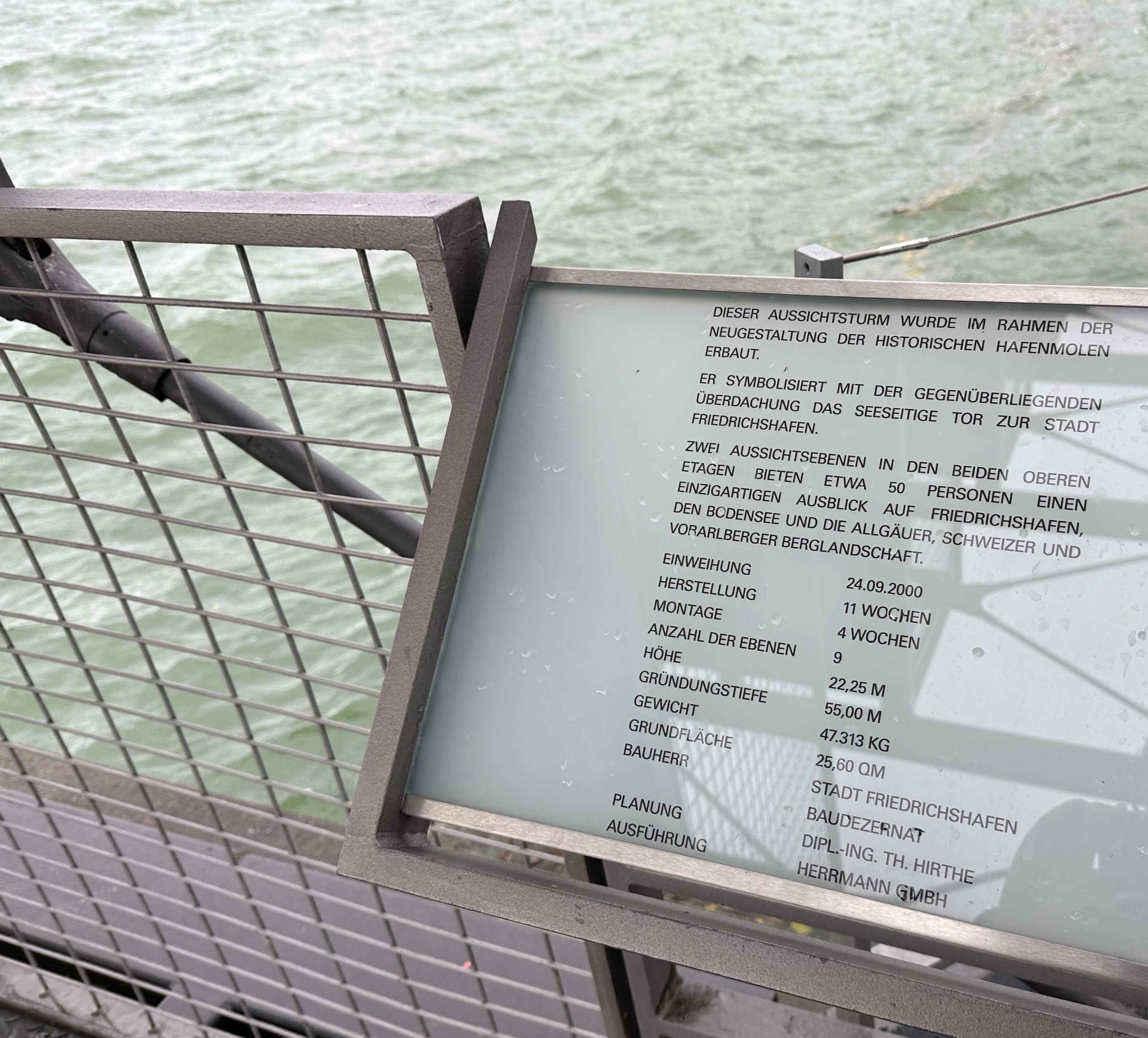 Eine Infotafel mit Text über den Aussichtsturm am Hafen von Friedrichshafen, aufgenommen aus der Nähe