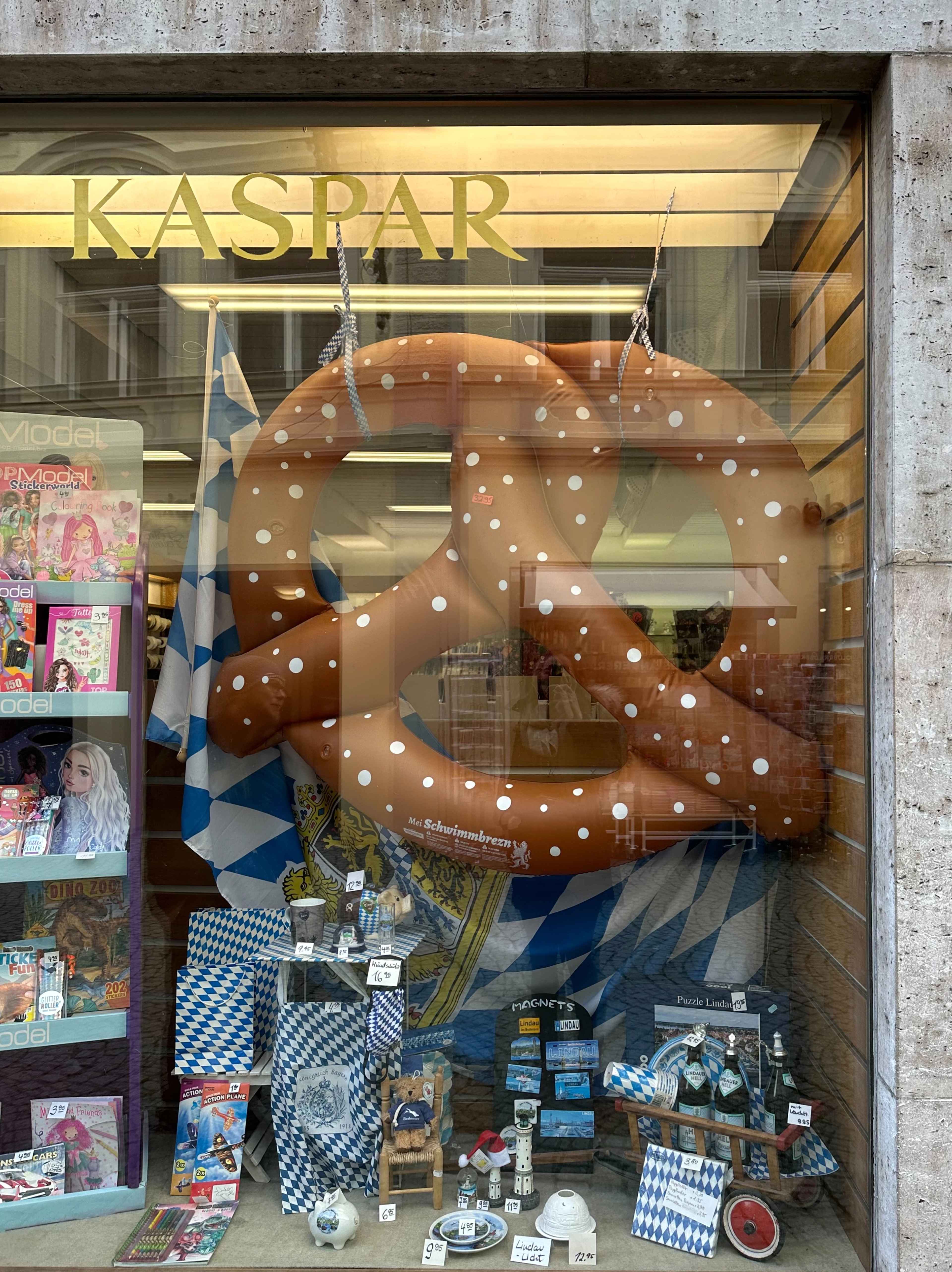 Ein Schaufenster mit einer riesigen Brezel-Dekoration. Im Hintergrund sind bayerische Fahnen und Souvenirs zu sehen.